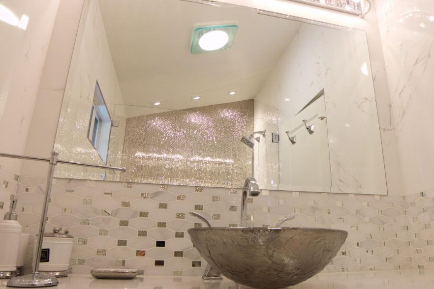 Modern bathroom with a glass sink, large mirror, tiled walls, and recessed ceiling light