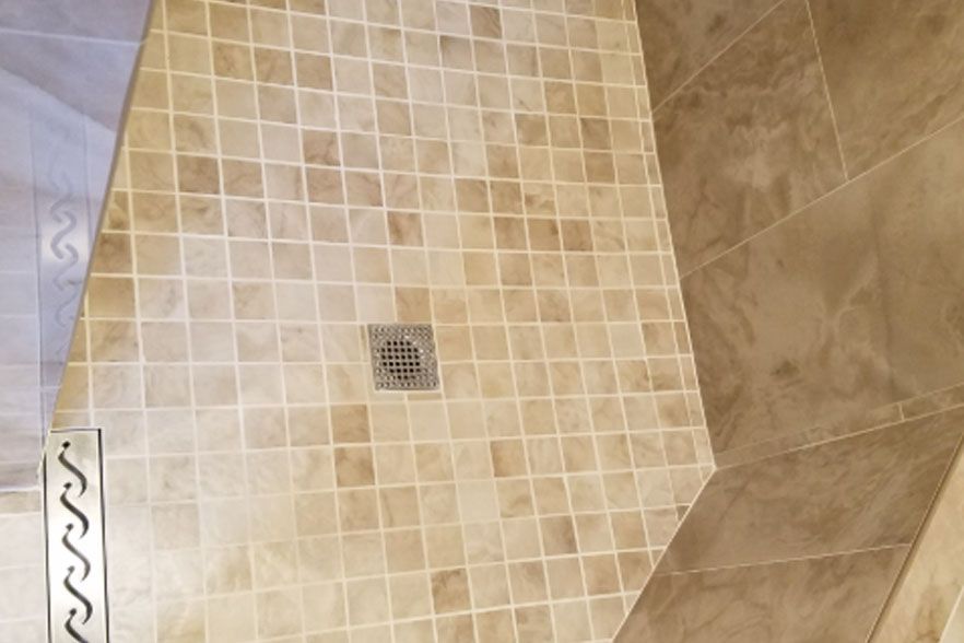Beige tiled shower floor with a square drain in the center