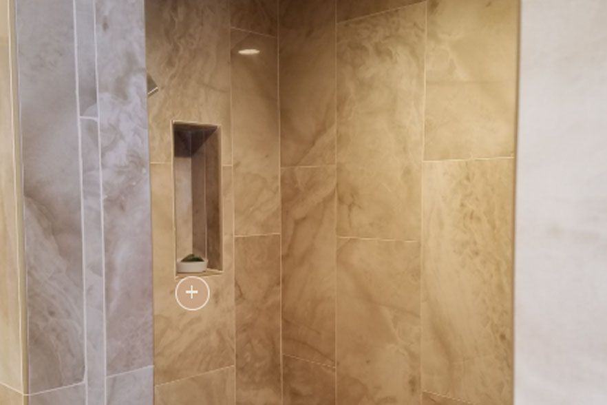 Walk-in shower with beige tile walls and a recessed shelf