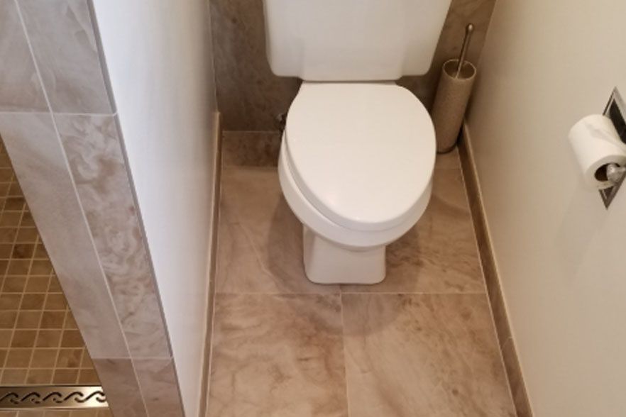 Small beige bathroom with a toilet beside a shower and toilet paper holder on the wall
