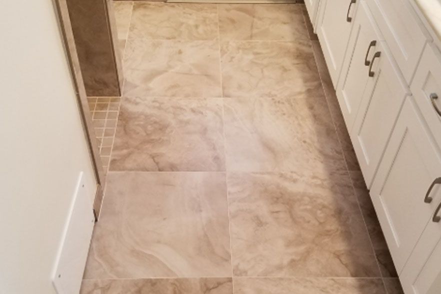 Tiled kitchen floor with a visible seam or patch near white cabinets and a countertop.