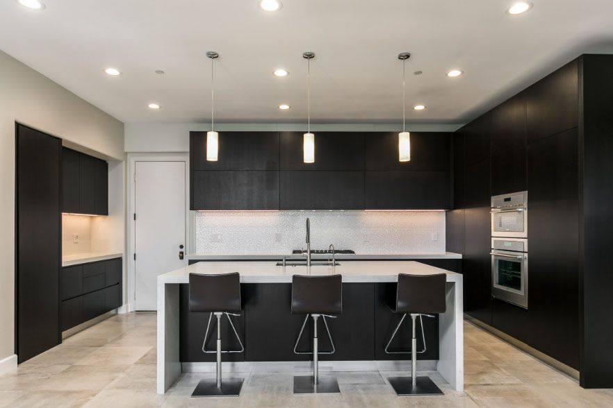 Modern black-and-white kitchen with a central island, three bar stools, and built-in appliances