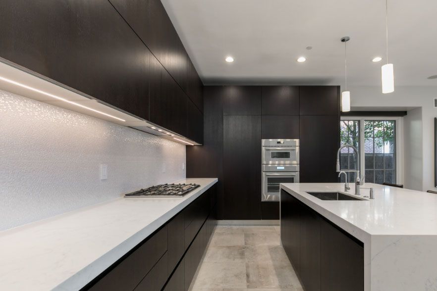 Modern black-and-white kitchen with island, built-in ovens, and large windows