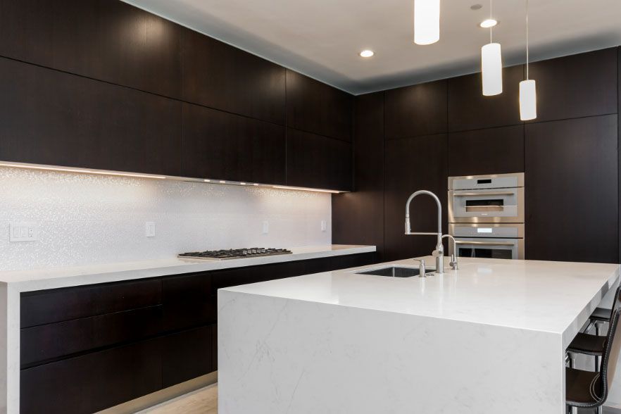 Modern kitchen with dark cabinetry, white island, and built-in appliances