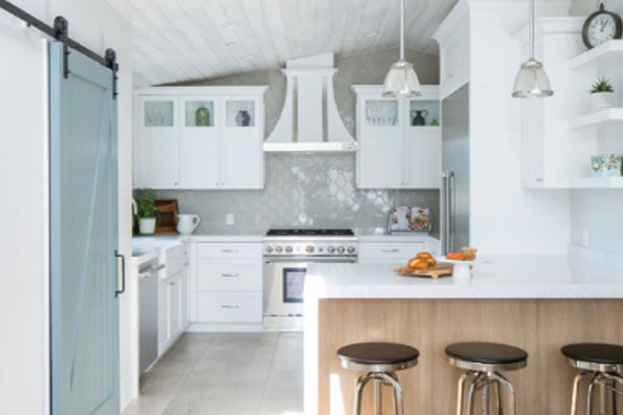 Bright white modern kitchen with island, bar stools, and stainless steel stove and hood