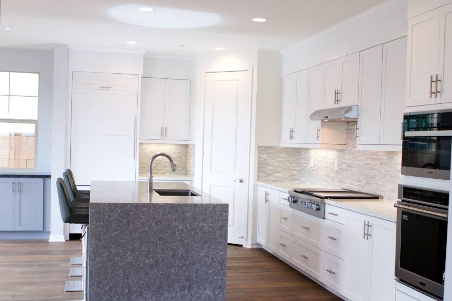 Bright modern white kitchen with island, stainless appliances, and gray countertops