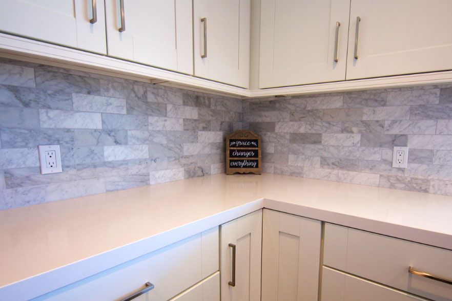 Corner kitchen countertop with white cabinets and gray tile backsplash