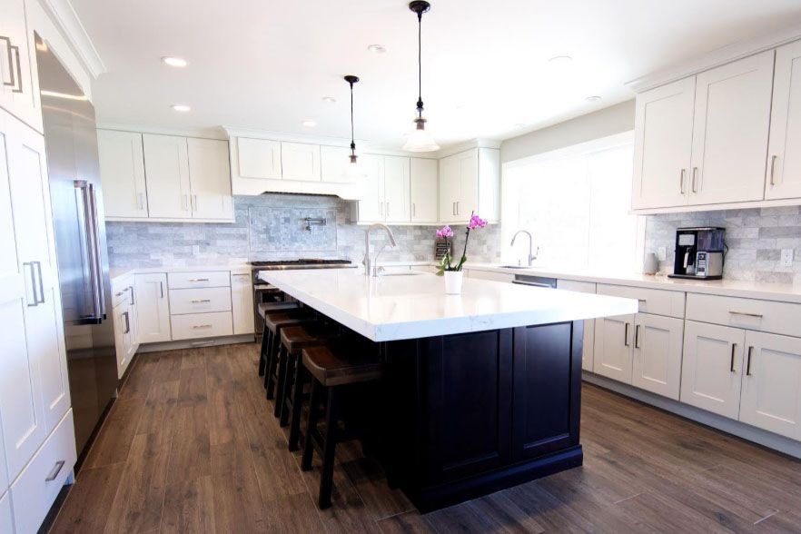 Bright modern kitchen with white cabinets, large island, and dark wood floors