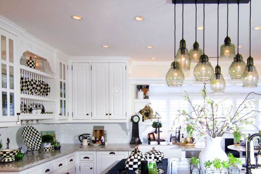 Bright white kitchen with black accents, hanging pendant lights, and floral centerpiece on the island