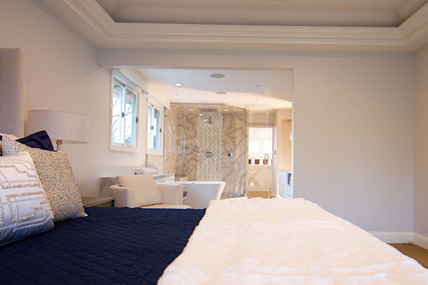 Modern bedroom with a large bed and an open view into a bright bathroom