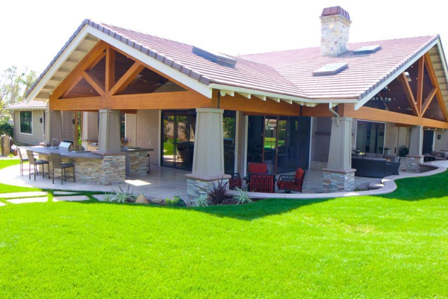 Single-story stone house with wood-trimmed porch and bright green lawn