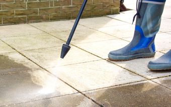 A person is using a high pressure washer to clean a tiled floor.