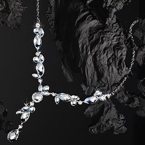 Crystal necklace draped over dark rocks on a black background