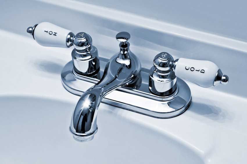 A bathroom sink with a chrome faucet and white handles