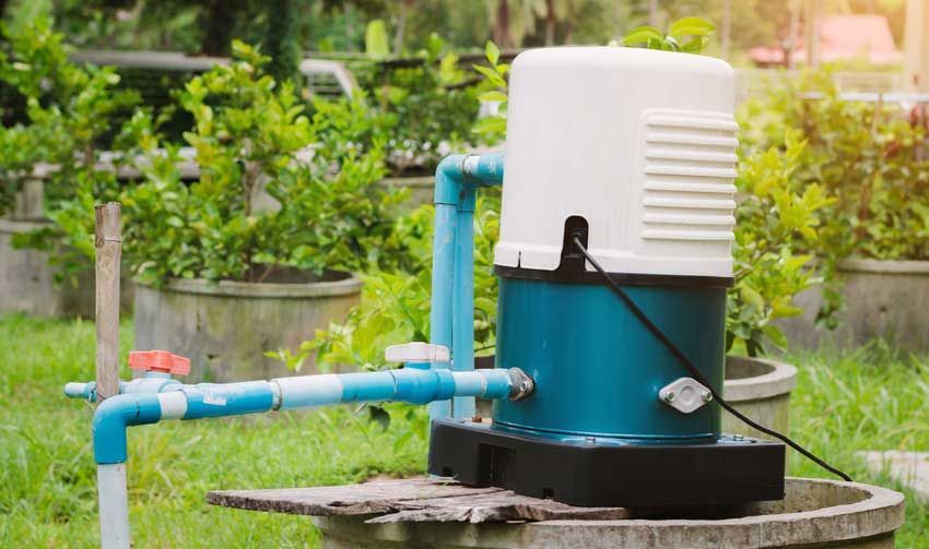 A water pump is sitting on top of a concrete platform in a garden.
