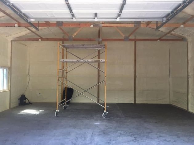 Empty garage interior with concrete floor and scaffolding centered under an open ceiling.
