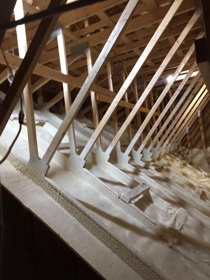 Attic interior with exposed wooden beams and diagonal metal braces over insulation