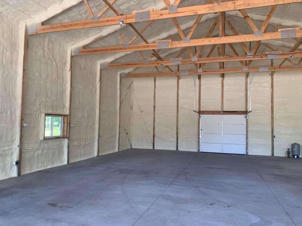 Empty insulated warehouse interior with exposed wooden trusses and a concrete floor