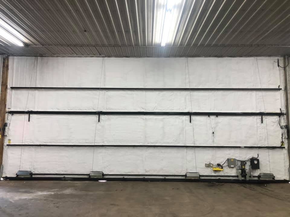 Empty industrial warehouse wall with overhead fluorescent lights and a small machine on the floor