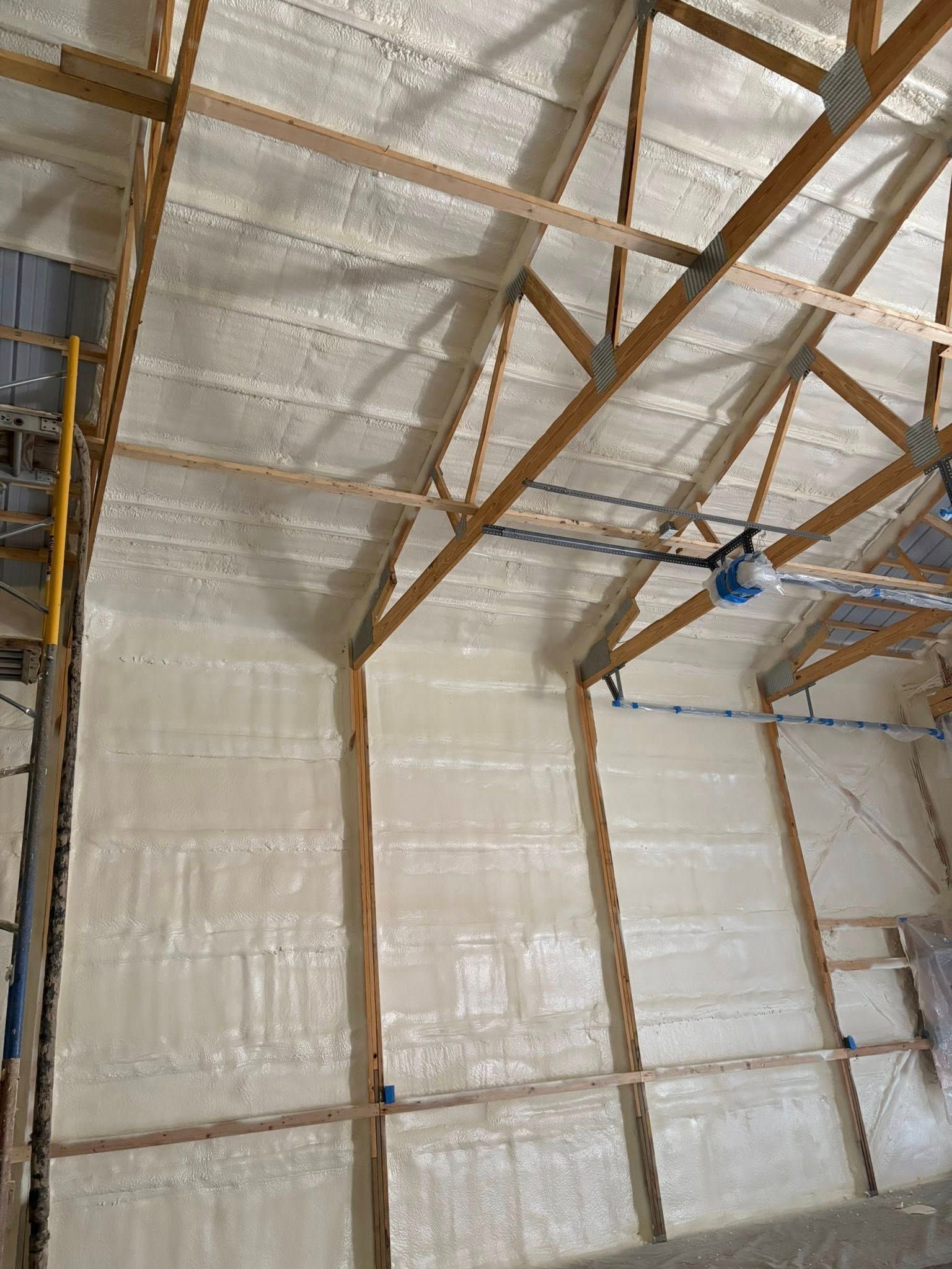 Insulated warehouse ceiling with wooden trusses and a hanging blue light fixture