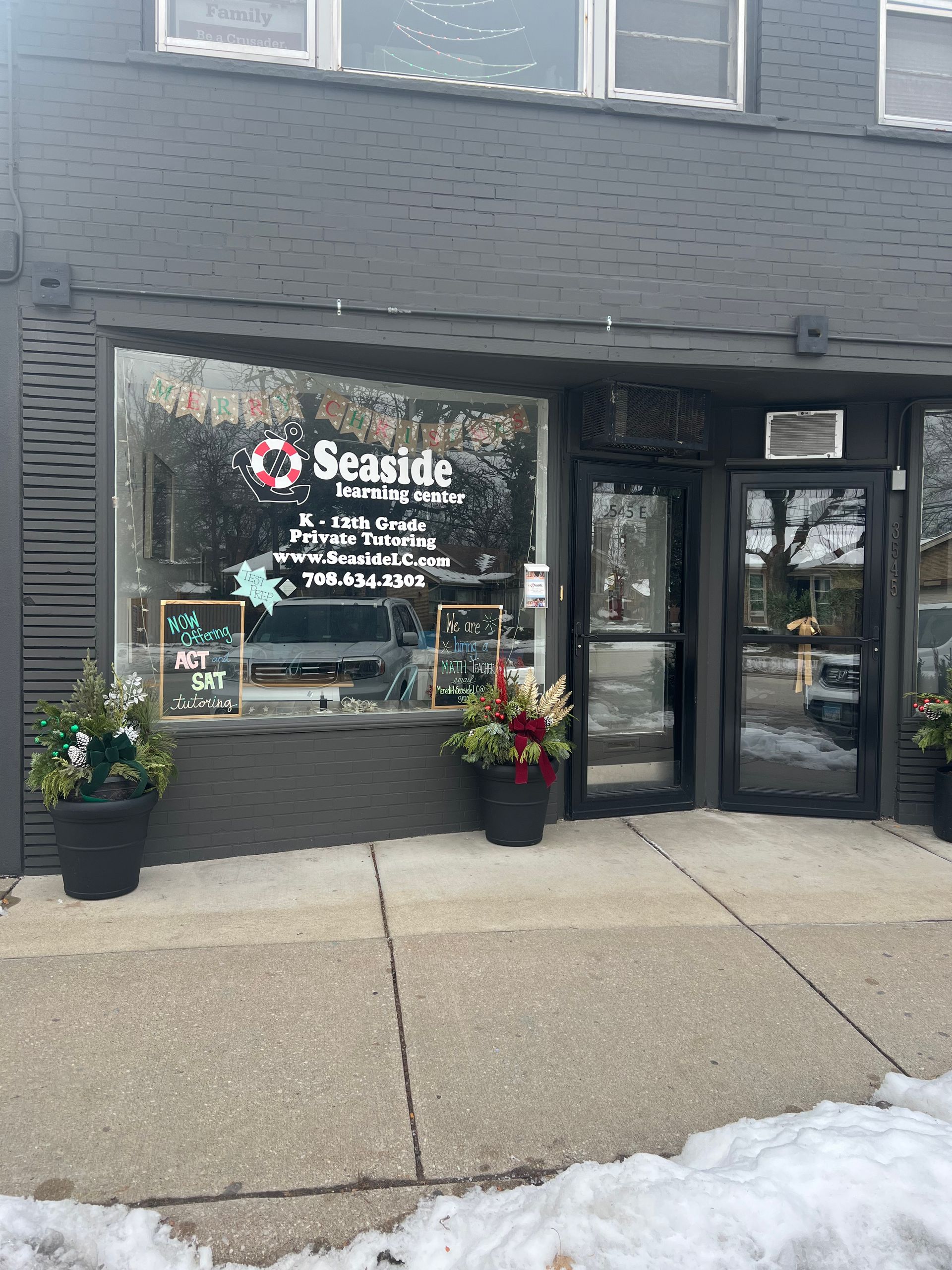 Seaside Furnishings storefront with a large display window, dark exterior, and potted plants.