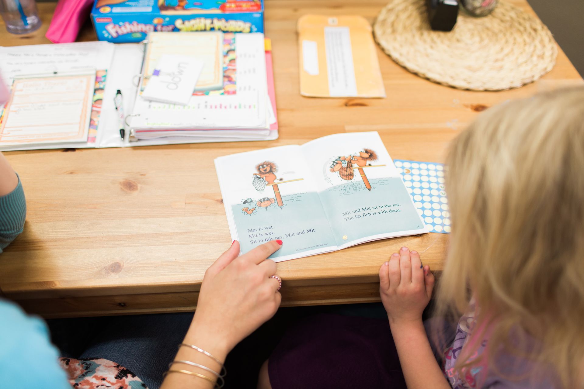 Woman and child reading a book together at a table.