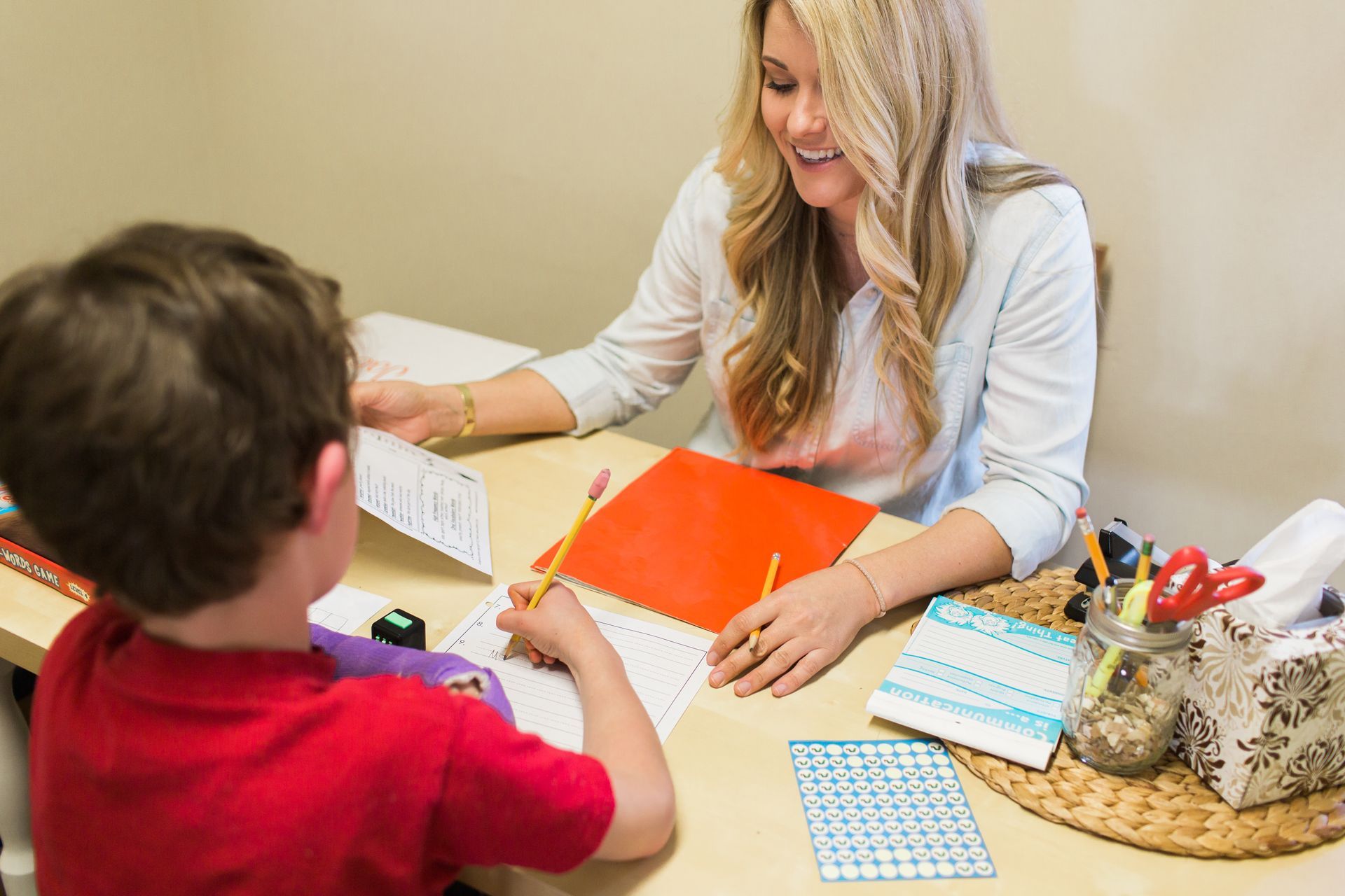 Two children playing with alphabet letter cards on a wooden table.