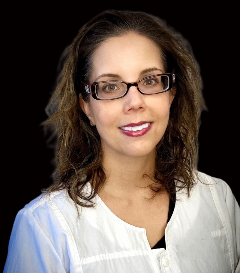 Portrait of a smiling woman with glasses and dark hair against a black background