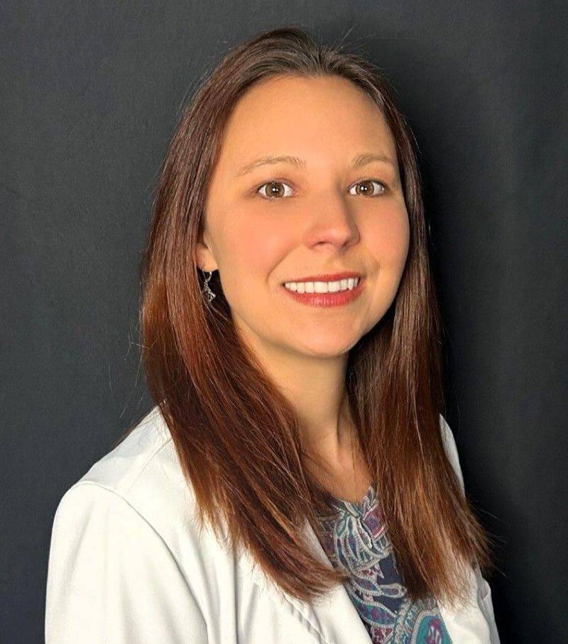 Portrait of a smiling woman in a white coat against a dark background