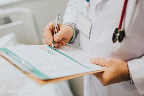 Doctor writing on a clipboard while holding a stethoscope in a clinical setting