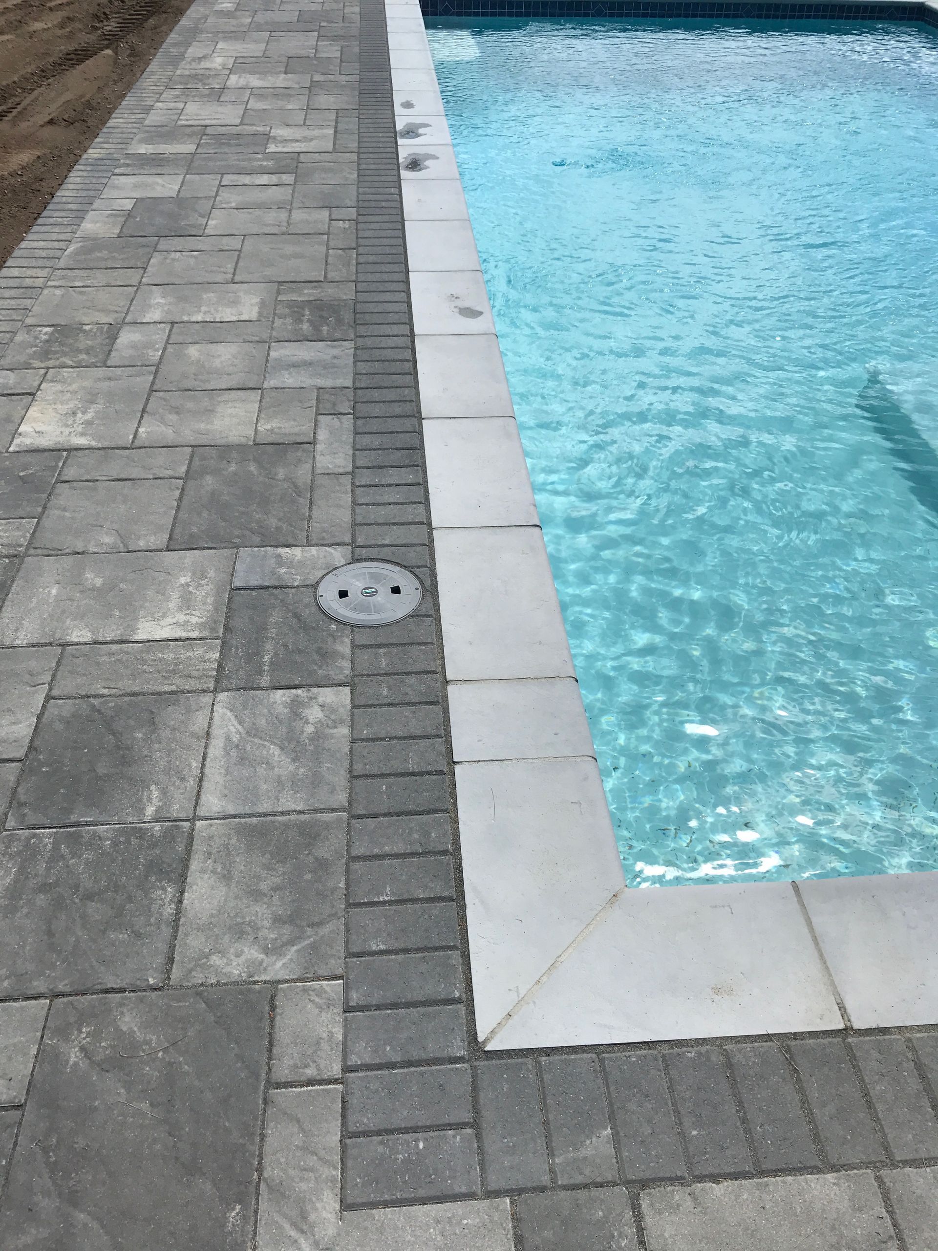 Stone pool deck beside clear blue swimming pool water