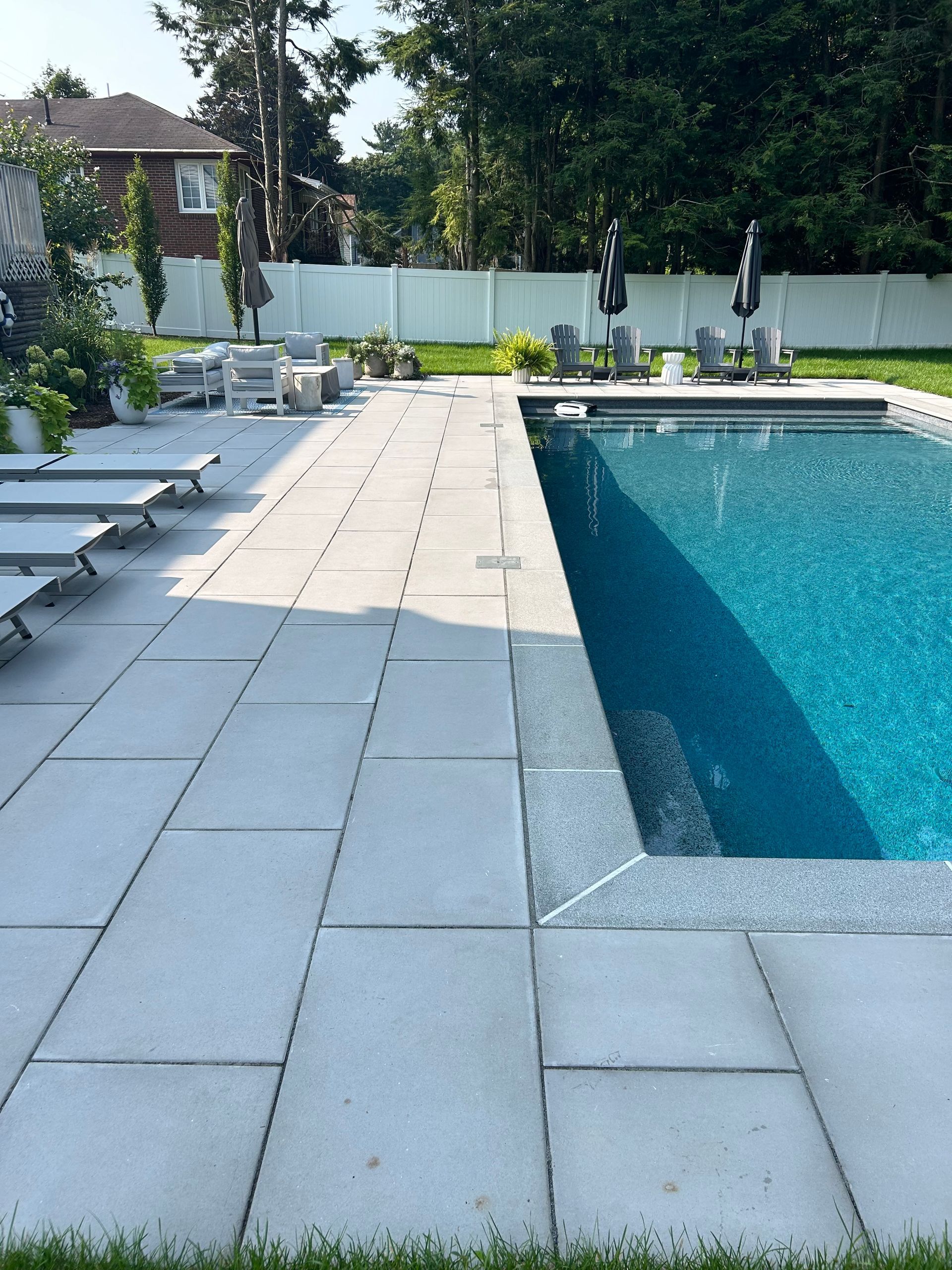 A large swimming pool surrounded by lawn chairs and umbrellas
