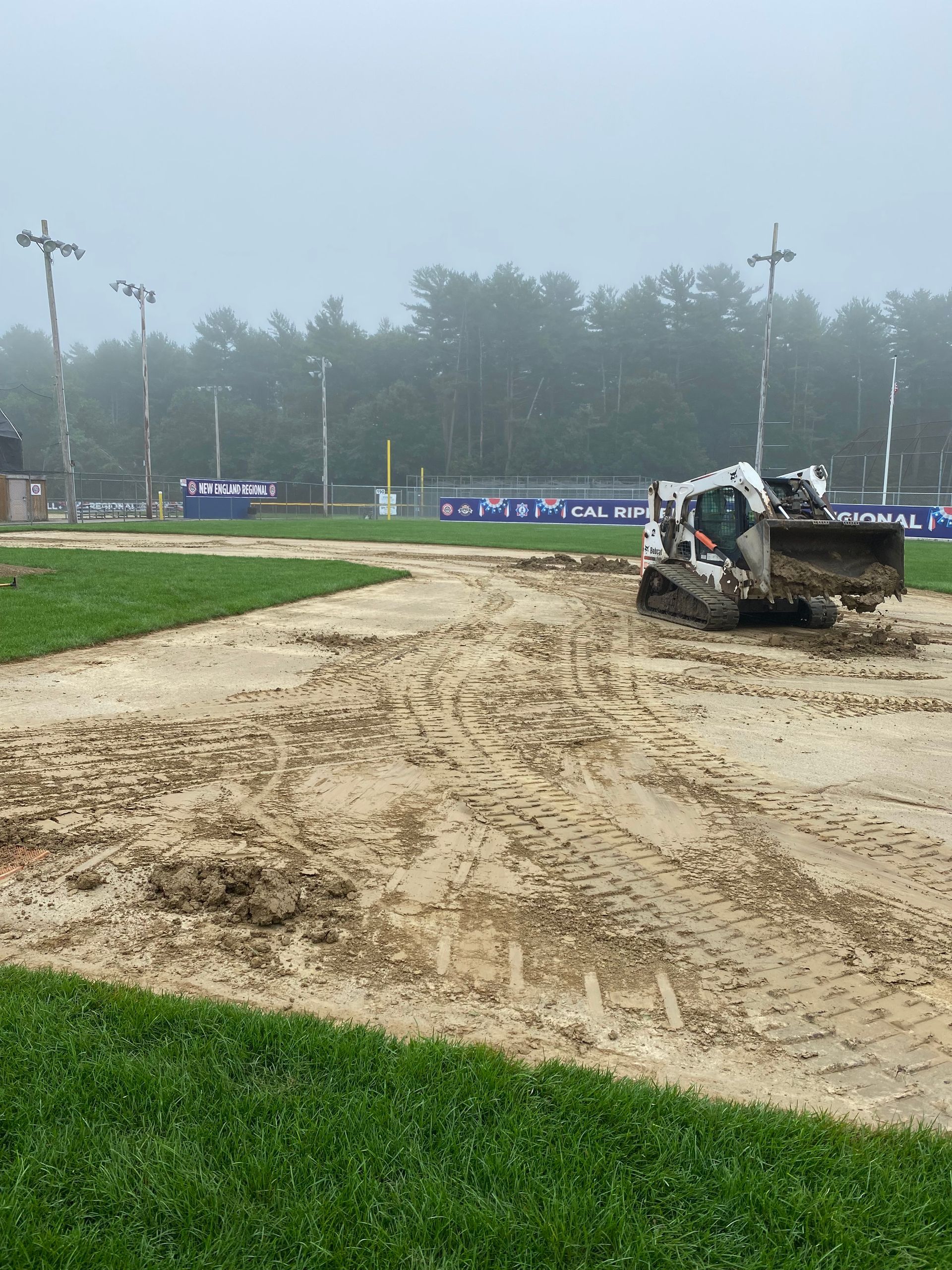 A bulldozer is moving dirt in a field on a foggy day.