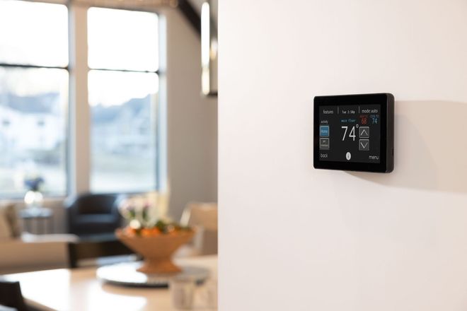 Smart thermostat mounted on a white wall in a bright, modern home interior