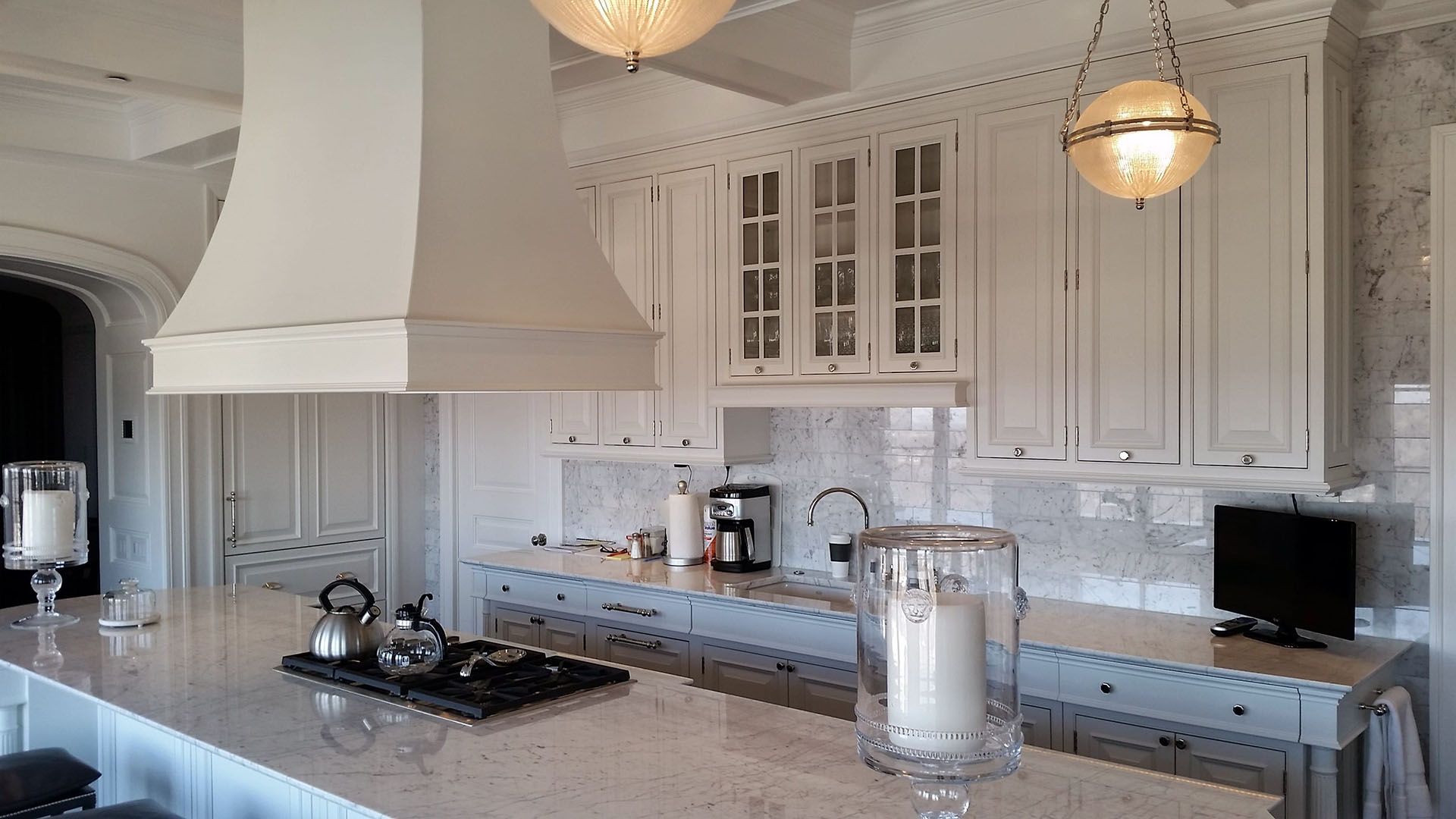A kitchen with white cabinets , granite counter tops , and a stove top oven.