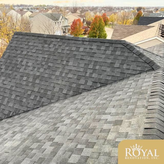 Gray shingled rooftop overlooking autumn trees and suburban houses