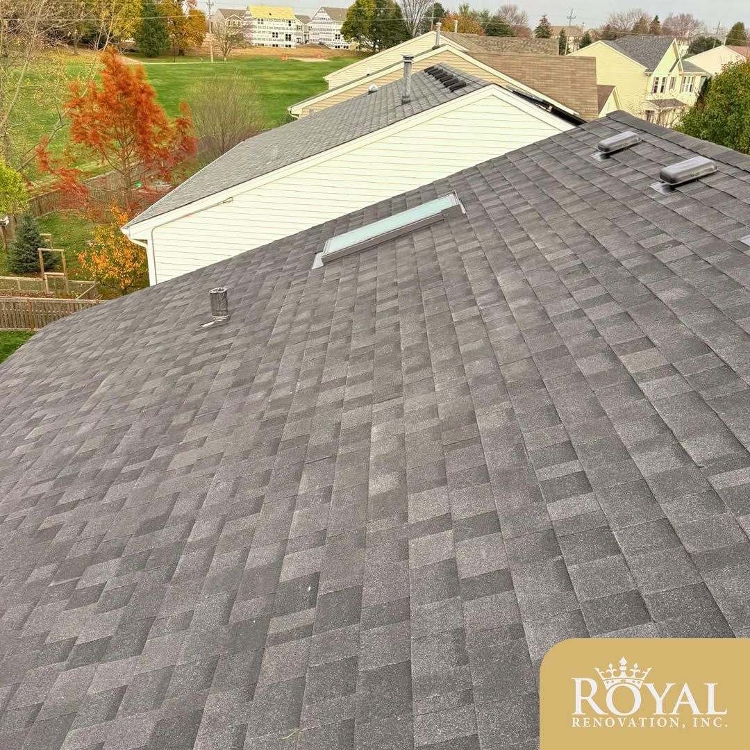 Gray shingled rooftop with skylights overlooking a suburban neighborhood in autumn