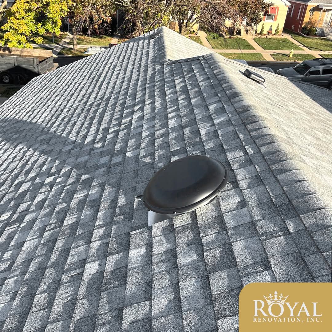 Gray shingled roof with a black roof vent on a sunny suburban house
