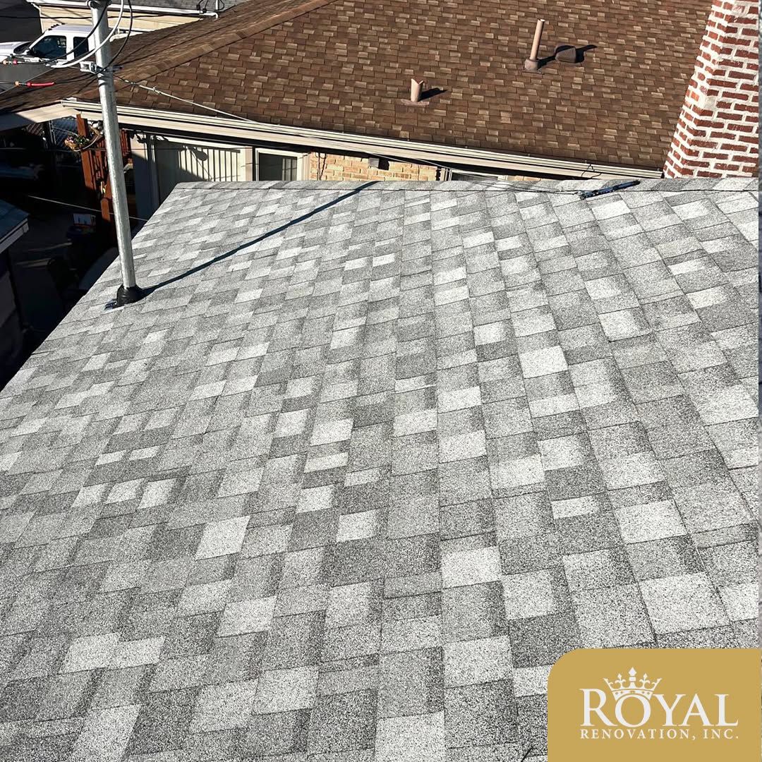 Gray shingled rooftop with a black cable, beside a tan roof and brick chimney under bright sunlight