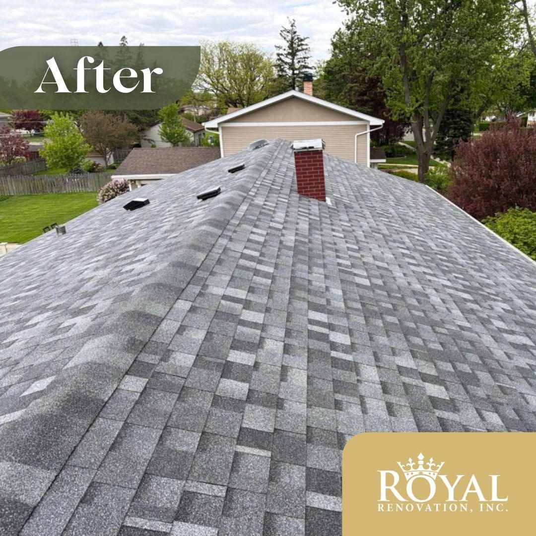 After view of a gray shingled roof with a chimney and backyard trees