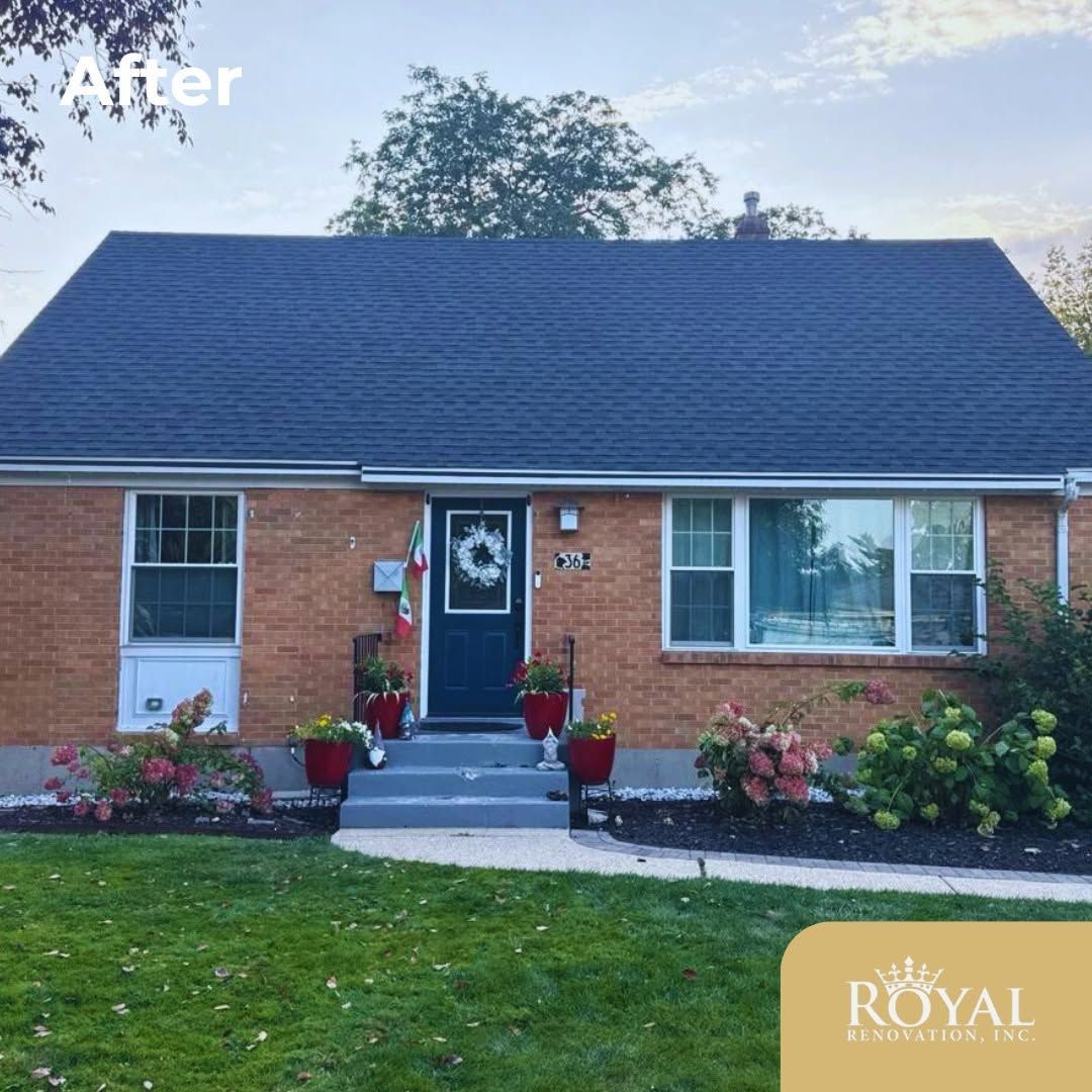 Brick house with dark gray roof, blue front door, white windows, and flowered front steps.