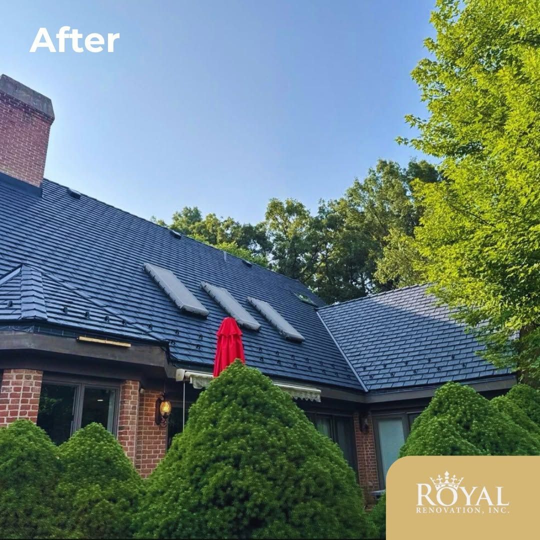 Brick house with dark roof, green trees, and a red umbrella on the patio under a clear blue sky.