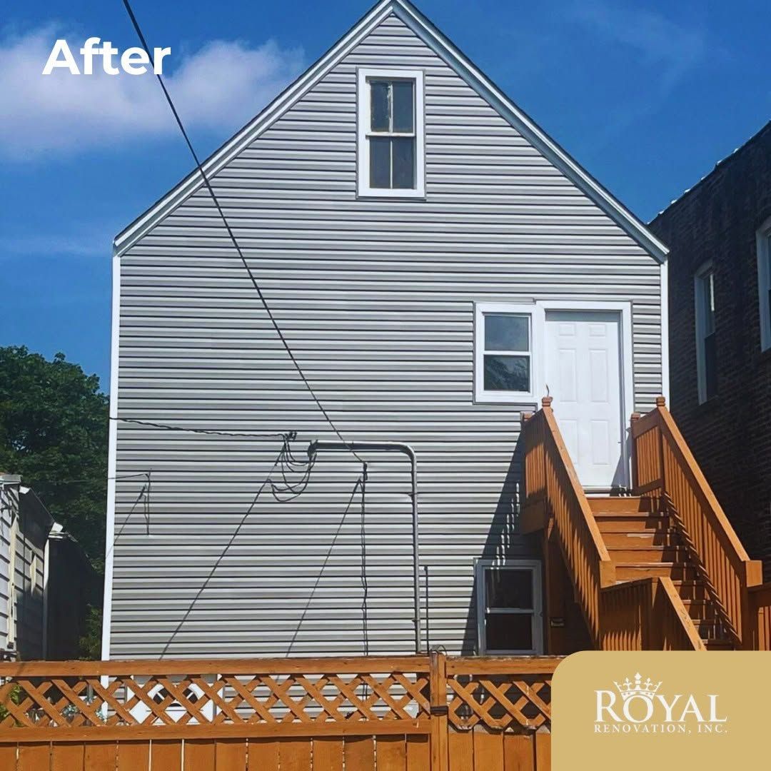 Gray house exterior with new white siding, wooden stairs, and a blue sky above