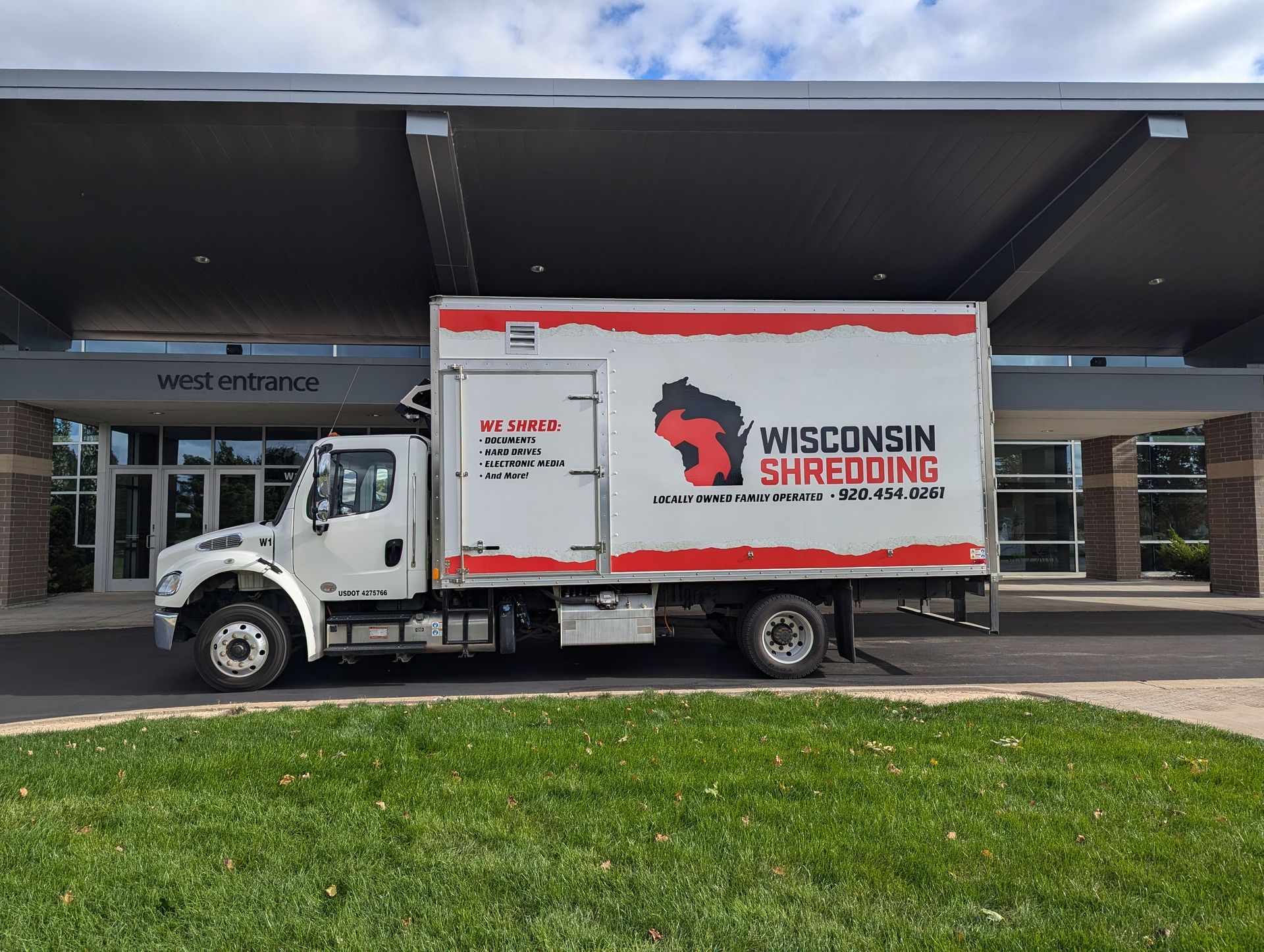 A wisconsin shredding truck is parked in front of a building