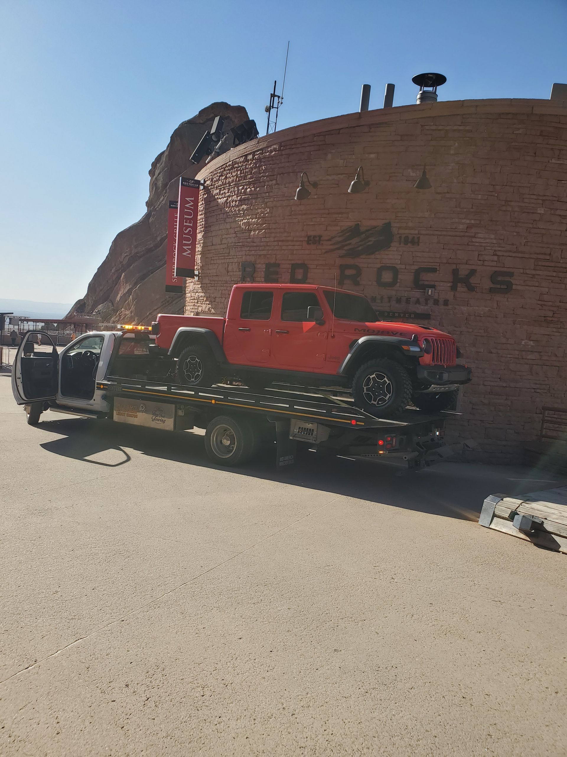 A red jeep is being towed by a tow truck