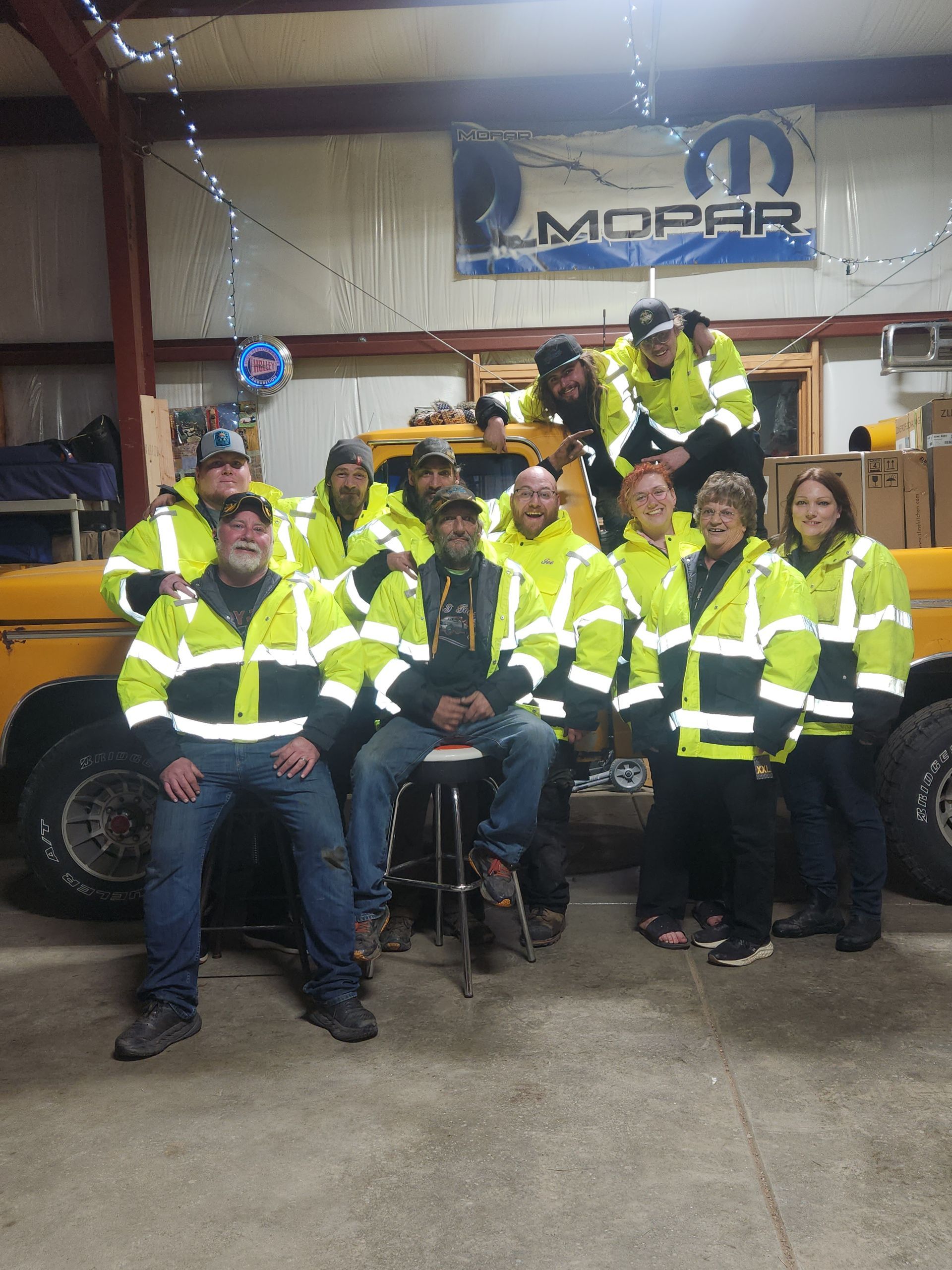 A group of people posing for a picture in front of a mopar sign