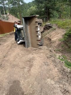 A bulldozer is on its side on a dirt road.