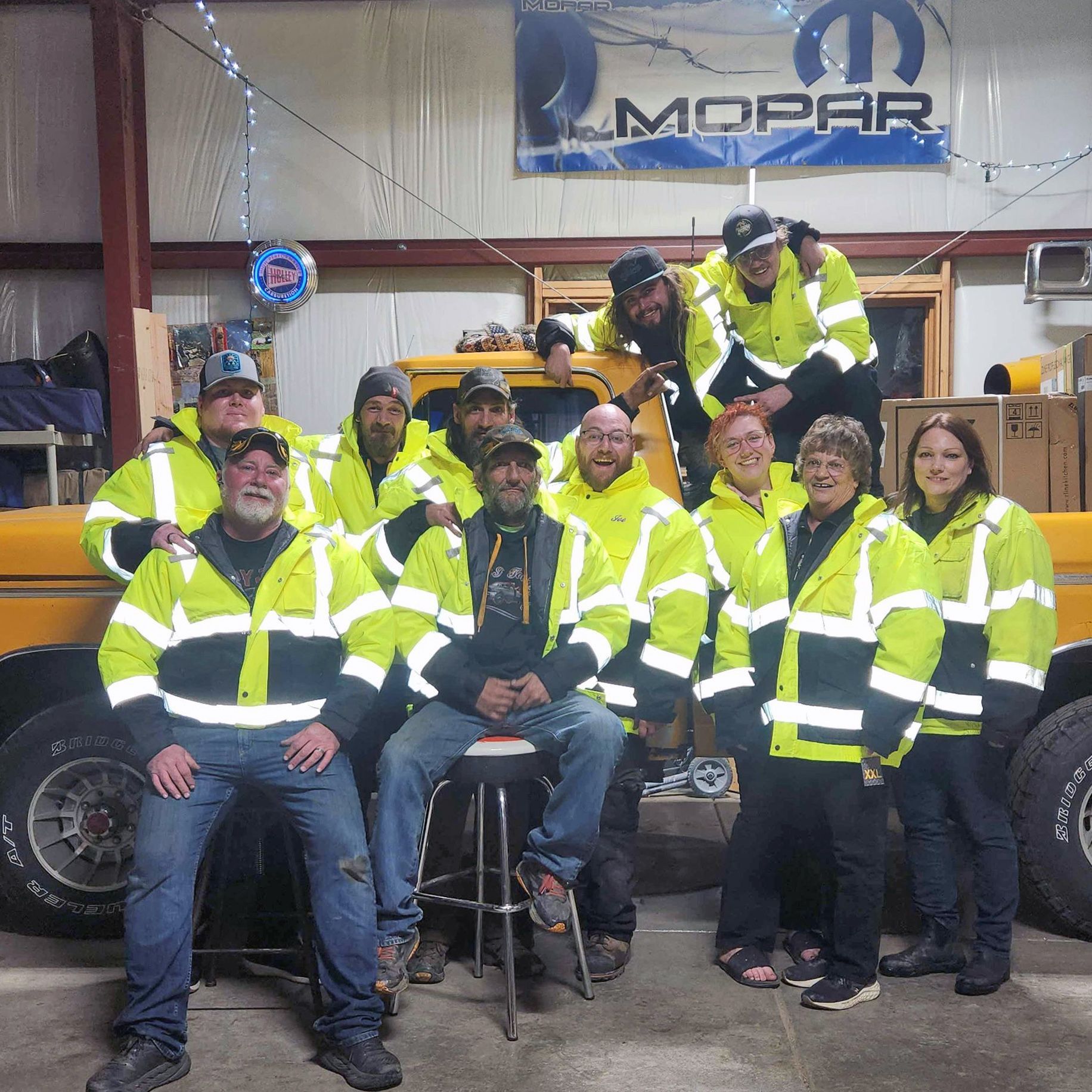 A group of people posing for a picture in front of a mopar sign