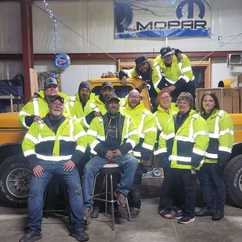 A group of people posing for a picture in front of a mopar sign