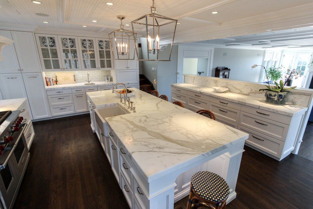 A large kitchen with white cabinets and marble counter tops.